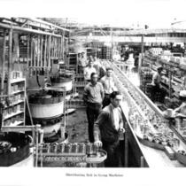 Cannery workers by distributing belt to syrup machines.