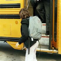 Child walking next to a school bus