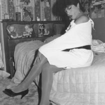 Female impersonator sitting on bed