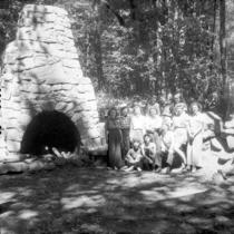 A group of young women posing by an outdoor stone hearth