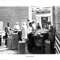 Cannery workers hand labeling cans.