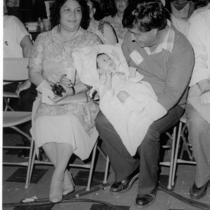 Cesar Chavez holding a baby on his lap.